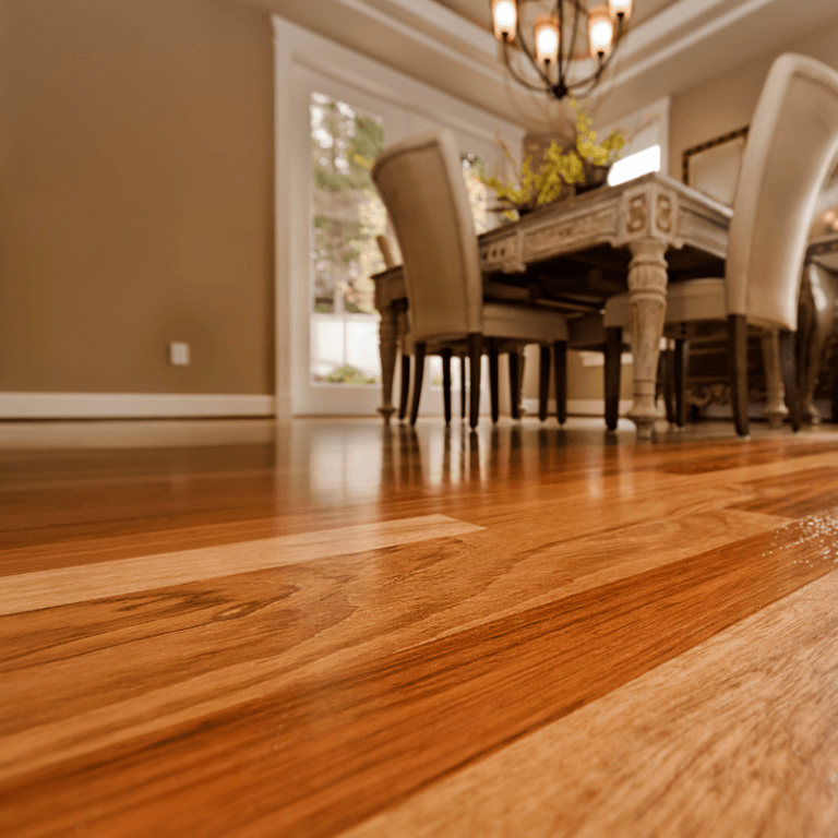 Close-up view of rich-toned hardwood flooring in a dining room, part of Simplicity’s hardwood flooring services