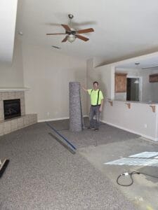 Walt standing in a living room leaning on a carpet roll during a residential carpet install