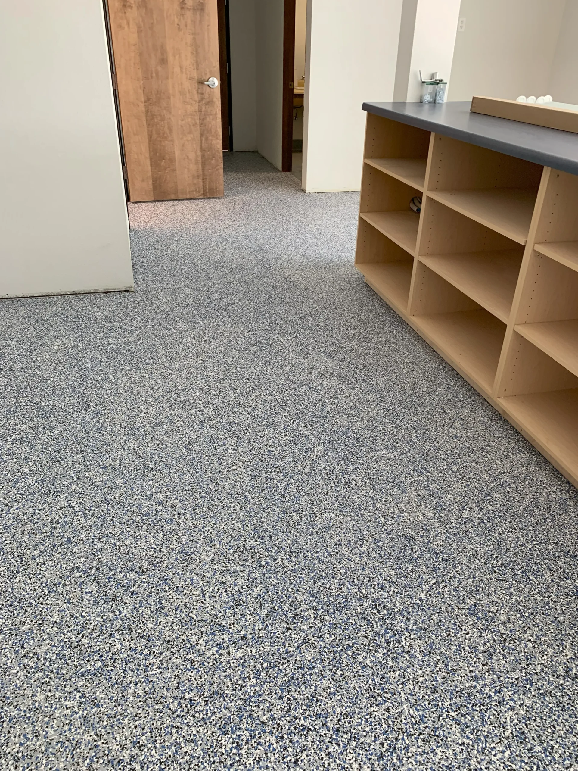 Durable speckled epoxy flooring in grey, black, and white installed in a commercial space