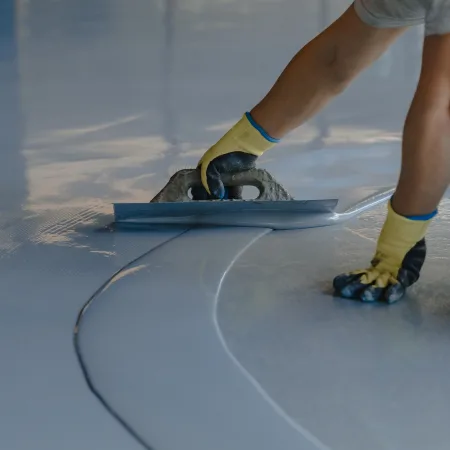 Installation of epoxy flooring, showcasing the maintenance costs of polished concrete vs. epoxy flake flooring