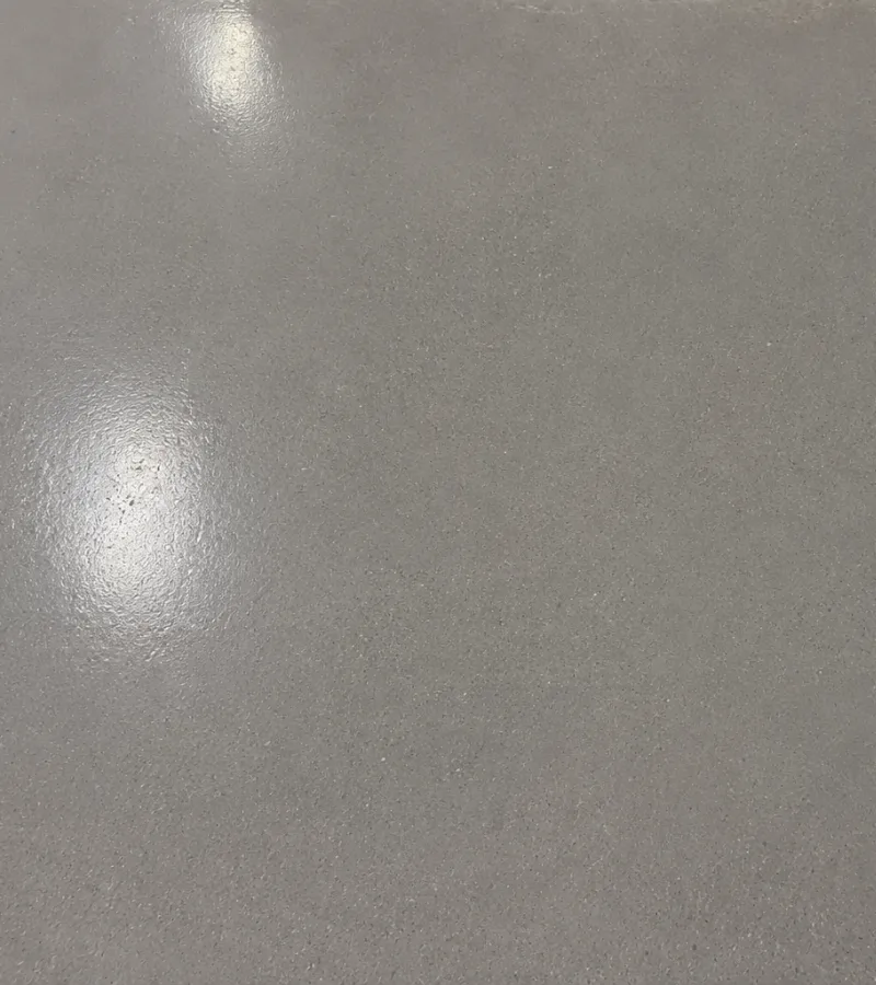 Gray polished concrete floor with subtle texture and reflections from overhead lighting.